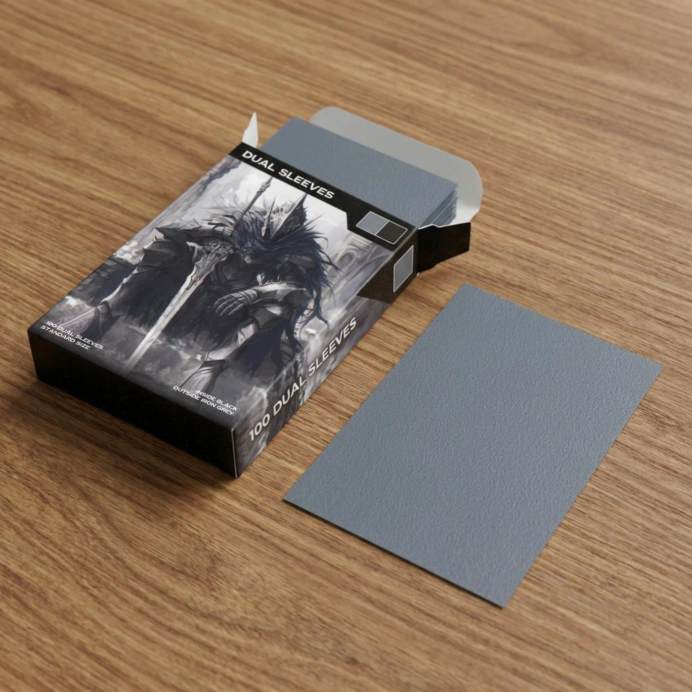 Realistisches Produktfoto der grauen Premium Dual Sleeves – Verpackung und Kartenhüllen in Nahaufnahme auf Holztisch, zeigt matte Oberfläche, Farbe und Qualität der Standard Size TCG Hüllen